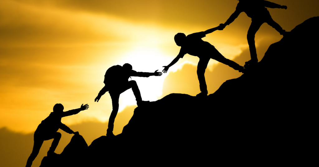 People helping each other climb mountain