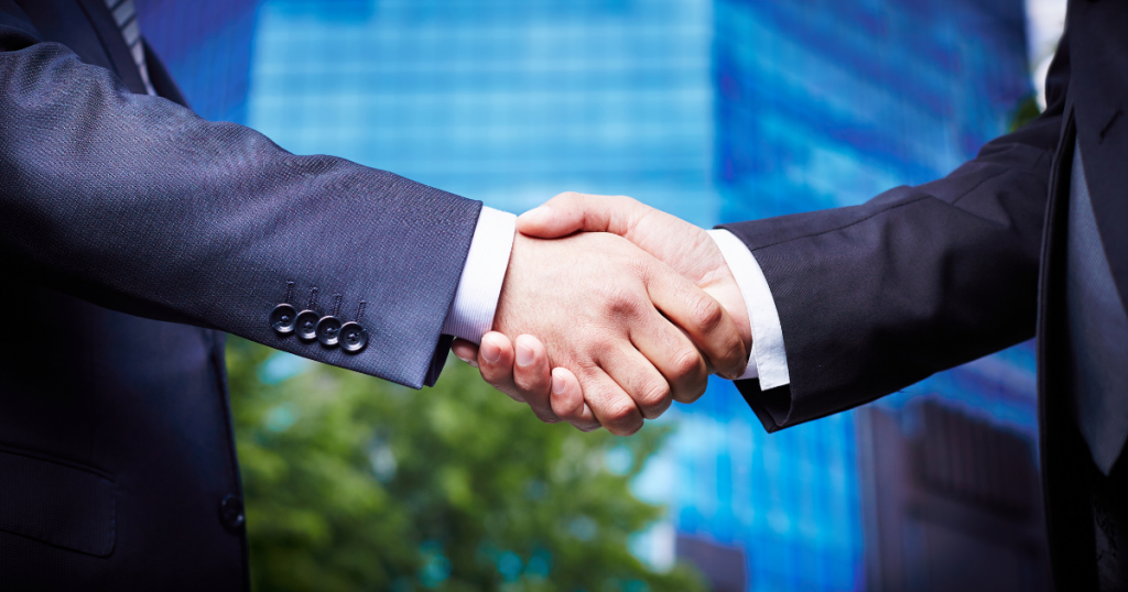 People shaking hands in front of corporate building