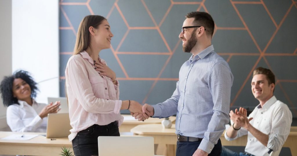 Manager appreciating an employee and other employees applauding them.