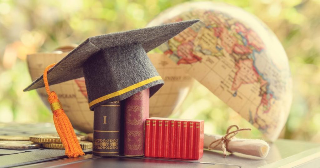 Graduation cap placed on books beside a globe
